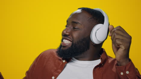 Porträt-Eines-Afrikaners,-Der-Mit-Kopfhörern-Auf-Gelbem-Hintergrund-Musik-Genießt.