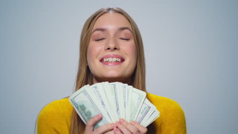 Portrait-of-young-smiling-woman-counting-money-on-grey-background-in-studio.