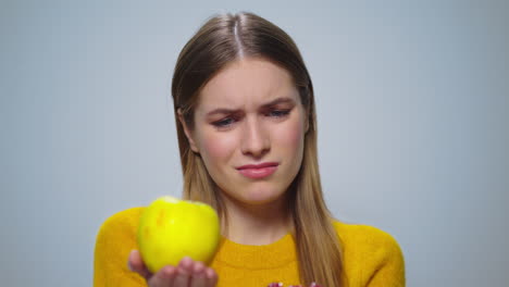 Portrait-of-pensive-woman-selecting-between-apple-or-cake-on-grey-background.