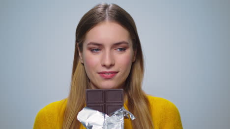 Portrait-of-smiling-woman-looking-with-chocolate-bar-at-camera-indoors