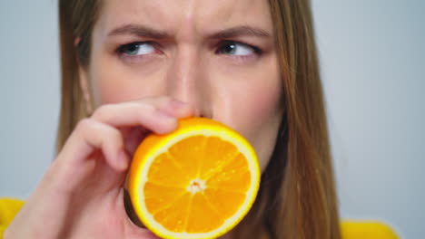 Closeup-positive-woman-making-funny-faces-with-orange-in-hands-in-studio.
