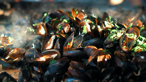 Closeup-mussels-with-herbs-cooking-on-frying-pan.-Clams-grilling-on-open-air