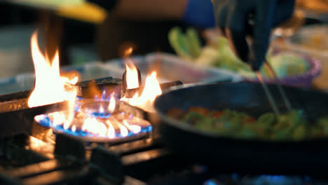 Closeup-chef-hands-stirring-vegetables-on-frying-pan.-Cook-preparing-meal