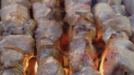 Closeup-pork-kebabs-barbecuing-on-metal-skewers.-Pork-meat-grilling-for-party