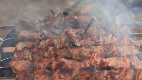 Closeup-smoked-bbq-flipping-over-charcoal.-Pork-kebabs-cooking-on-grill-outdoor