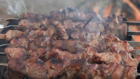 Closeup-pork-shashlik-cooking-on-brazier-outdoor.-Pork-kebabs-roasting-on-grill