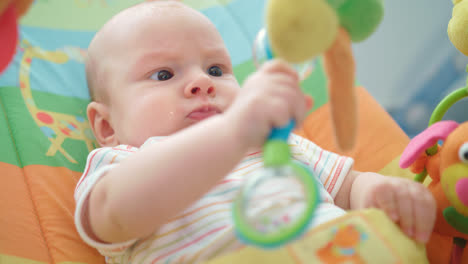 Portrait-of-newborn-kid-playing-with-toy.-Close-up-of-baby-boy-playing-toy