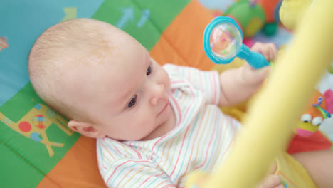 Cheerful-baby-lying-on-colorful-bed.-Infant-boy-playing-toy