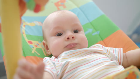 Little-baby-face.-Close-up-of-cute-infant-lying-on-colorful-mat