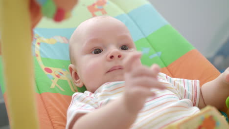 Little-baby-face.-Close-up-of-cute-infant-lying-on-colorful-mat