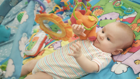 Infant-baby-playing-on-colorful-mat.-Close-up-of-cute-baby-boy-play-with-toy