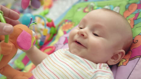 Playful-baby-smiling-on-development-mat.-Portrait-of-happy-baby