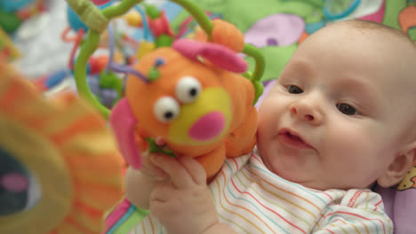 Sweet-baby-playing-toy.-Close-up-of-cute-baby-boy-lying-on-colorful-mat