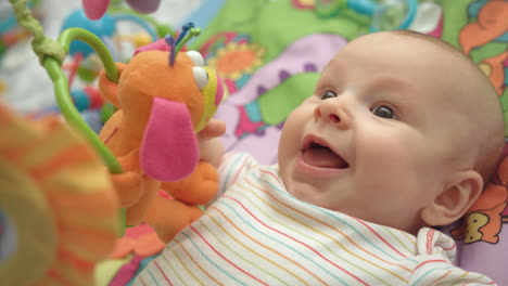 Close-up-of-little-boy-face.-Portrait-of-happy-baby-on-colorful-mat-with-toys
