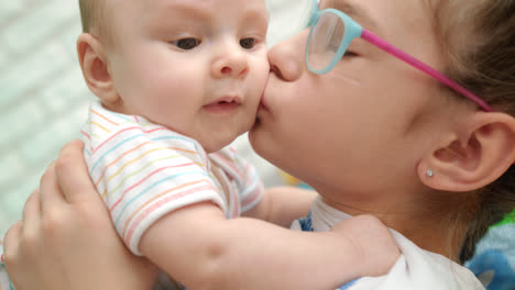 Sister-kissing-baby-brother.-Sweet-family-love.-Older-sister-hugging-cute-infant