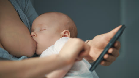 Nahaufnahme-Einer-Frau,-Die-Ihr-Mobiltelefon-Benutzt,-Während-Sie-Ihr-Neugeborenes-Baby-Stillt