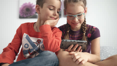 Portrait-of-sister-and-brother-looking-at-mobile-phone.-Kids-playing-video-games