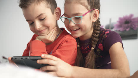 Happy-children-watching-movie-on-smart-phone-at-home.-Portrait-of-smiling-kids