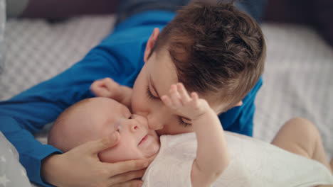 Portrait-of-boy-kissing-infant-at-sofa.-Lovely-child-kissing-baby-brother-on-bed