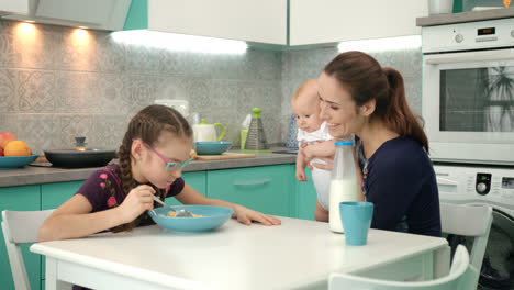 Family-breakfast-at-morning.-Girl-eating-corn-flakes-with-milk-at-kitchen-table