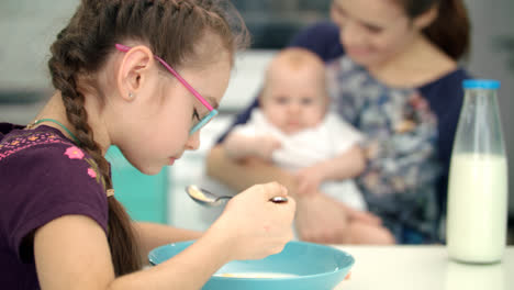 Girl-eating-breakfast-with-mother-and-baby.-Kid-have-lunch-at-kitchen