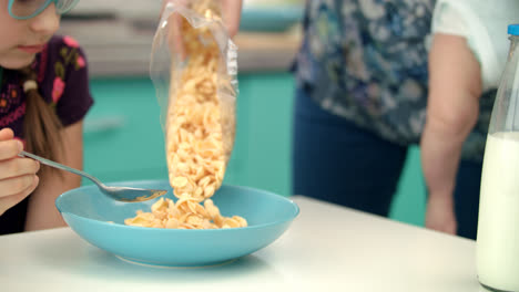 Mutterhände-Gießen-Cornflakes-In-Blaue-Schüssel.-Frühstück-Für-Kind-Vorbereiten