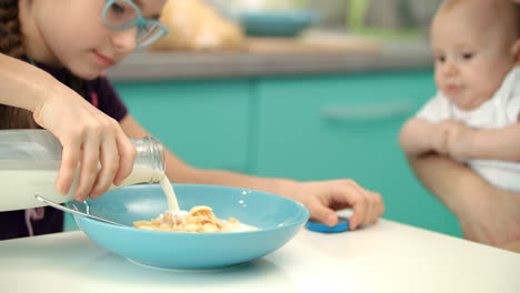 Girl-pouring-milk-into-glass-bowl-of-corn-flakes.-Healthy-lifestyle