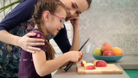 Mother-learning-dauther-using-knife.-Little-girl-cutting-apple-slice