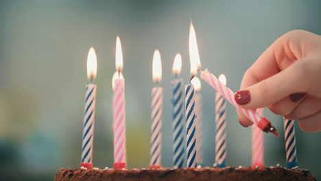 Frauenhand-Legte-Kerzenflamme-In-Geburtstagstorte.-Brennende-Kerze-Im-Geburtstagskuchen