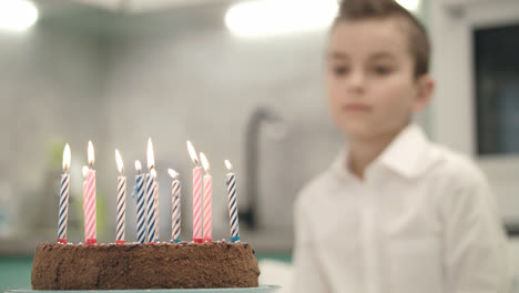 Boy-looking-on-birthday-cake-with-candle-flames.-Happy-birthday-concept