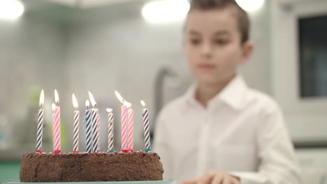 Boy-looking-on-birthday-cake-with-candle-flames.-Happy-birthday-concept