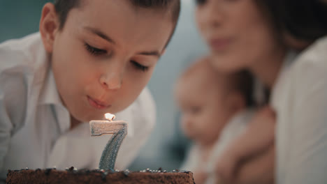 Boy-blowing-candle-on-birthday-cake-at-family-party.-Happy-birthday-party