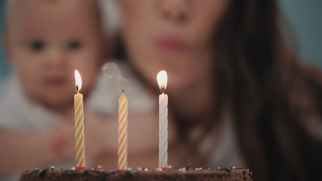 Mutter-Bläst-Drei-Kerzen-Auf-Die-Geburtstagstorte-Ihres-Babys.-Baby-Geburtstagsparty-Konzept