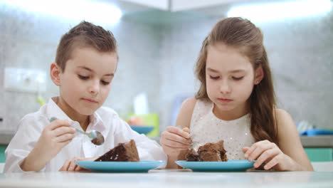 Siblings-eating-birthday-cake-at-kitchen.-Children-eat-chocolate-dessert-at-home