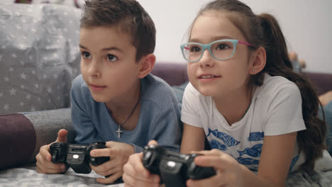Children-playing-video-games.-Kids-lying-on-sofa-with-controller-in-hands
