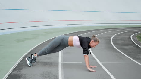 Handicapped-woman-doing-plank-on-hand-at-stadium.Lady-exercising-on-sports-track