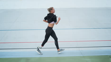 Disabled-female-runner-starting-to-run-on-track.-Jogger-exercising-at-stadium