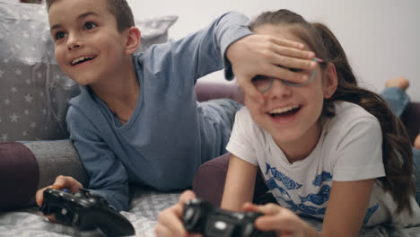 Kids-playing-video-games.-Brother-close-eyes-sister.-Children-have-fun-together