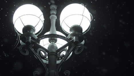 Glowing-street-lamp-in-snowy-night.-Close-up-street-lantern-in-night-snowflakes