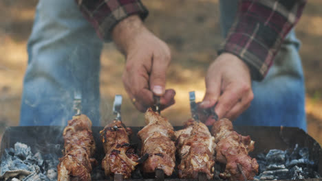 Man-grilling-meat-bbq-on-outdoor-grill.-Shish-kebab-on-skewers-grilled-on-picnic