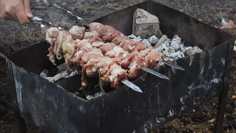 Hands-putting-meat-skewers-on-charcoal-grill.-Cooking-meat-barbecue-on-grill
