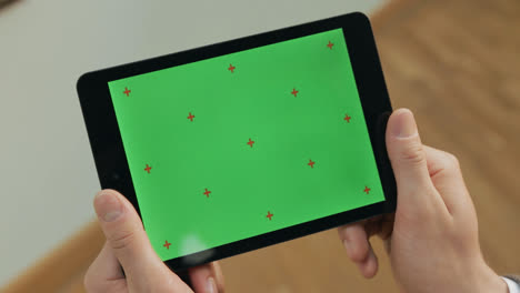 Male-hands-holding-tablet-with-green-screen.-Man-gesturing-on-tablet-screen