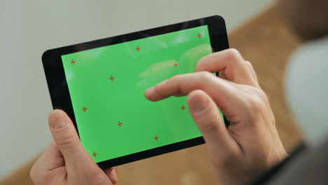 Männliche-Hand-Berührt-Green-Screen-Tablet.-Nahaufnahme-Des-Grünen-Chroma-Key-Tablet-Bildschirms