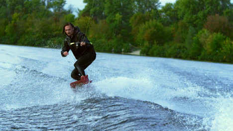 Man-riding-board-on-waves.-Wake-boarding-rider-training-on-wakeboard-boat