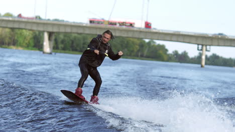 Joyful-man-wakeboarding-on-city-river.-Extreme-entertainment-on-water