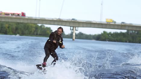 Joyful-man-wakeboarding-on-city-river.-Extreme-entertainment-on-water