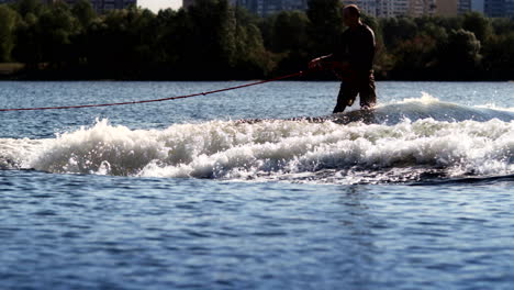 Wake-surfer-riding-board-on-river-in-sunny-day.-Extreme-lifestyle-concept