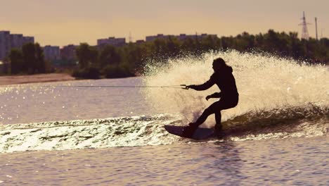 Man-wakeboarding-on-water-at-sunset.-Wakeboarder-making-tricks