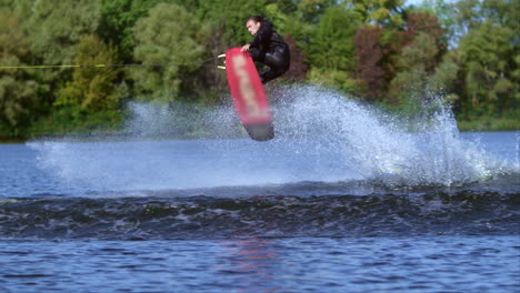 Wakeboarder-making-tricks-on-water.-Sportsman-wakeboarder-jumping-through-wave