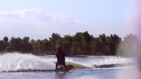 Man-wakeboarding-on-waves.-Water-skiing-on-lake-behind-boat.-Wakeboarder-surfing